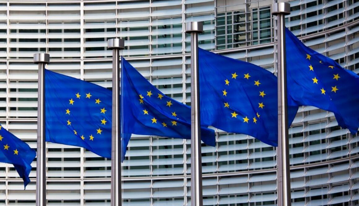 European Union flags flying outside the European Commission building, marking the EU Action Plan on AI Cybersecurity